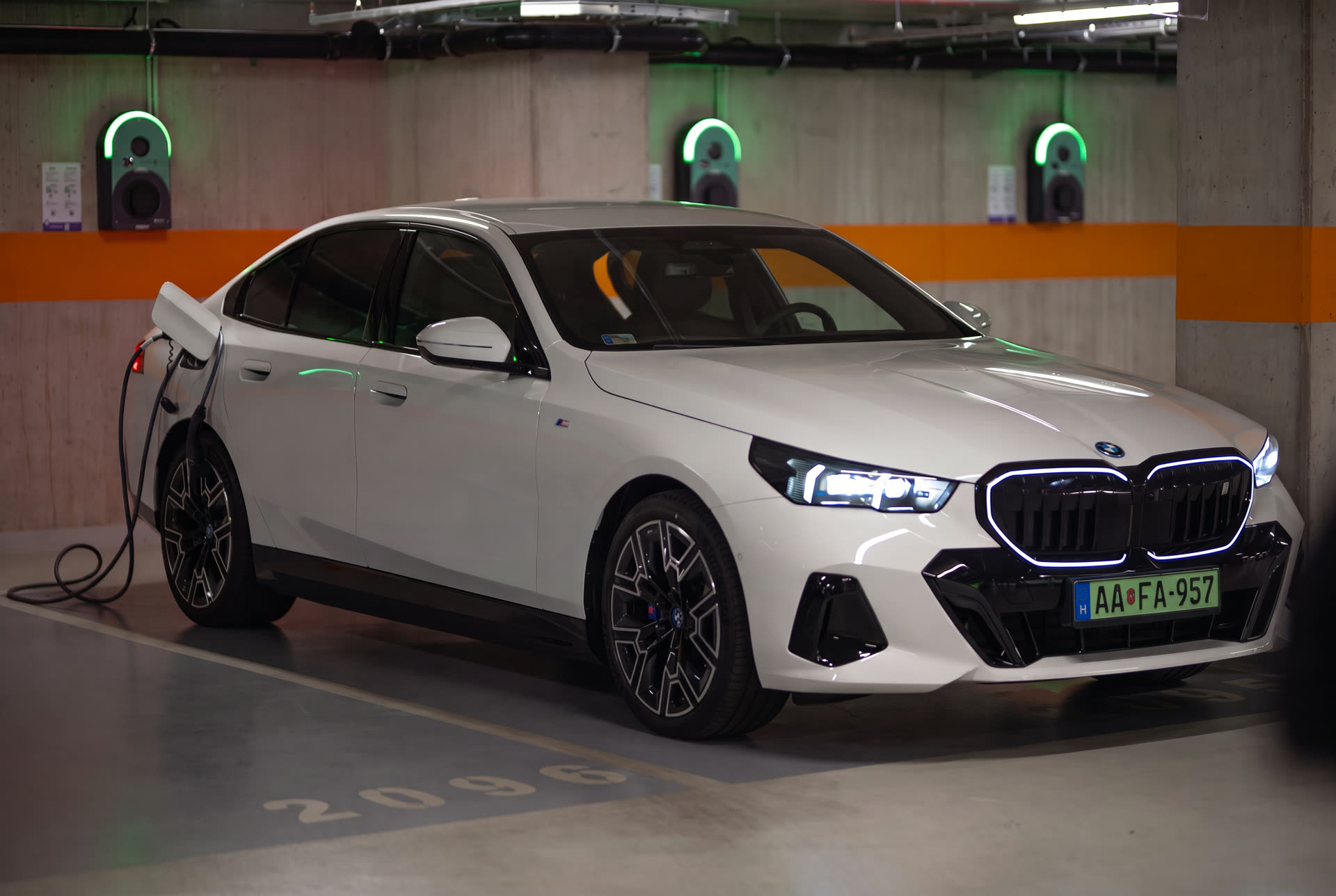 White electric BMW charging at a wallbox in an underground garage